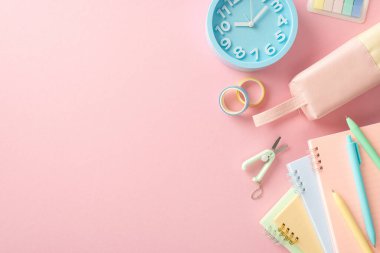 Mükemmel çalışma alanı oluşturun! Kırtasiye malzemeleri, fotokopi kitapları, kalem kutusu, saat, kalem, yapışkan bant, pastel pembe arka planda makas. Boş alan metin veya reklam yerleştirme için fırsat sağlar