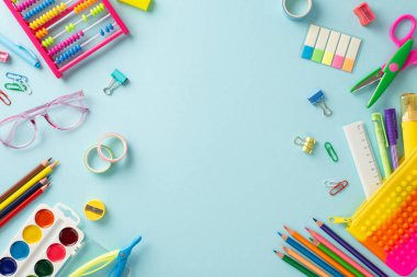 Erken eğitim dünyasına bu tepeden tırnağa perspektifle dalın: huzurlu bir pastel mavi zemin üzerine kurulmuş parlak okul malzemelerinin bir çeşidi, metin veya reklamlar için telif alanı sunuyor