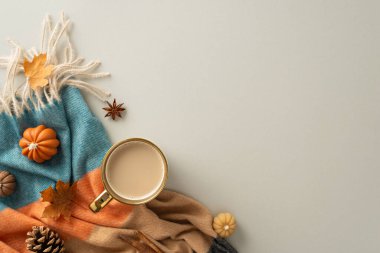 Sonbaharda evde olmanın rahatlığı. Yukarıda bir fincan sıcak kahve, yamalı battaniye, balkabağı şekilli mumlar, akçaağaç yaprağı ve izole edilmiş gri arka planda bulunan aromatik baharatlar.