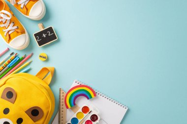 Meraklı zihinler büyüyor. Okul gereksinimleri ve ayakkabılarla dolu şirin bir çocuk sırt çantasının en üst görüntüsü. Pastel mavi bir zeminde yürümek için, metin veya promosyon içeriği için mükemmel.