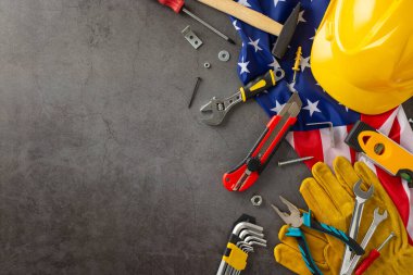 Amerikan İşçi Bayramı 'nda inşaat işçilerinin paha biçilmez katkılarını takdir etmek. Bayrak, kask, eldiven ve grunge desenli gri beton üzerinde inşaat aletleri. Reklam veya metin için ideal