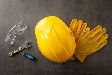 Amerikan İşçi Bayramı 'nda inşaat işçilerinin önemli rolünün farkına varmak. Sarı başlık ve eldivenlerin üzerinde fotoğraf ve grunge desenli gri beton arka plan üzerinde inşaat araçları
