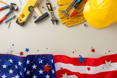 İnşaat işçilerinin olduğu İşçi Bayramı: üst görünüm fotoğrafı, açık gri izole bir arkaplanda bayrak, kask, eldiven ve inşaat aletleri sergilenmesi. İşçi Bayramı pazarlama veya metin yerleştirme için mükemmel