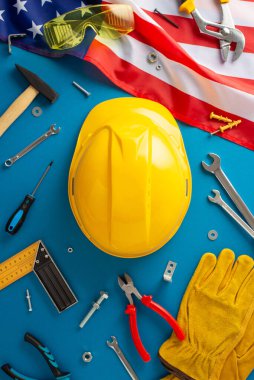 İşçi Bayramı otomotiv tamiri teması. Amerikan bayrağının üst görüntüsü, tamirci aletleri, anahtarlar, soket takımı, tornavida, bujiler, eldivenler, güvenlik gözlükleri, miğfer. Mavi arkaplan, otomatik tamir hizmetleri için alan