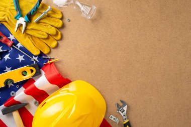 İşçi Bayramı atölyesi konsepti. ABD bayrağı, tornavida, pense, boru anahtarı, çivi, ruh seviyesi, çekiç, iş eldiveni, güvenlik gözlükleri. Plywood arkaplanı, tamir servisi tanıtımı için alan