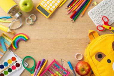 Sınıfın kırtasiye malzemesi. Canlı aksesuarlar, albüm, boya seti, klavye, büyüteç, abaküs, tebeşir, ayı şekilli çanta, su şişesi, ahşap masa üzerindeki elmalar, yazı veya reklam çerçevesi
