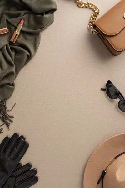 Sonbahar kadın giyimi konsepti. Geniş kenarlı keçeli şapka, deri eldivenler, şık gözlükler, rahat eşarp, bej çanta, tarafsız arkaplanda boş alan ve mesaj veya reklam için kullanılan ruj.