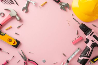 İşçi bayramında kadın işçilerin etkisinin farkında olmak. Pembe arkaplan, miğfer ve yapı araçlarına sahip üst görünüm fotoğrafı, reklamlar veya metinler için kopyalama alanı sunuyor