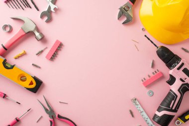 İşçi Bayramı 'nda kadınların katkısını kutluyoruz. Pembe izole edilmiş arka planda inşaat aletleri olan bir miğfer ve reklam veya metin için yer sunan bir üstten çekim