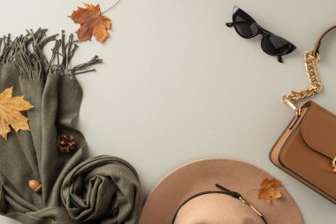 Şık mevsimlik aksesuarlar. Üst görüntü, modaya uygun bir keçeli şapka, rahat bir eşarp, zarif eldivenler ve açık gri arka planda moda promosyonları için boş çerçeveli şık bir el çantası sunar.