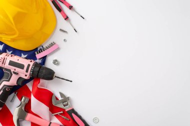 İnşaat temalı İşçi Bayramı anısına: Dikkatleri bu üst görünüm ile çekin, beyaz zemin üzerinde bir bayrak, iş kaskı, eldiven ve araçlar sergileniyor. İşçi Bayramı kampanyaları ve mesajları için harika