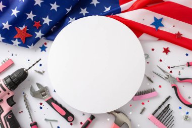 Amerikan İşçi Bayramı 'nda kadın işçilerin anısına. Amerikan bayrağı, konfeti yıldızları ve pembe yapı araçlarını beyaz arka planda gösteren yüksek açılı fotoğraf, reklam veya metin yerleştirme için telif alanı sağlıyor