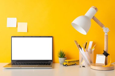 Üretken çalışma düzeni. Kırtasiye malzemesi, takvim, akademik şapka, saksı, dizüstü bilgisayar, lamba, okul otobüsü oyuncağı, sarı arka planda yapışkan notlar. Metin için alanı kopyala