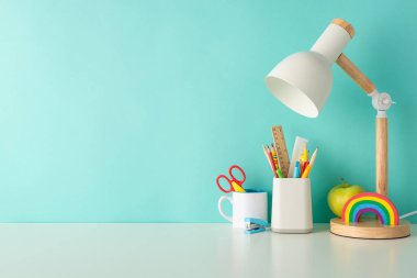 Renkli ofis gereçleri, organizatör ve lambayı içeren bu yan görünüm fotoğrafıyla verimli öğrenme alışkanlıkları edinin, metin veya reklam için geniş bir alan eşliğinde mavi bir zemin üzerinde