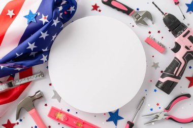 İşçi Bayramı 'nda kadınların ithafını kutluyoruz. Beyaz izole arkaplanda bir Amerikan bayrağı ve inşaat araçlarının yukarıdaki fotoğrafı, reklamlar veya metin yerleştirme için boş yuvarlak çerçeve sağlıyor