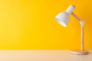 Eğitimsel ortam. Masa lambası fotoğrafı sarı bir arka fona yerleştirilmiş. Okul temalı mesajlar veya promosyonlar için ideal