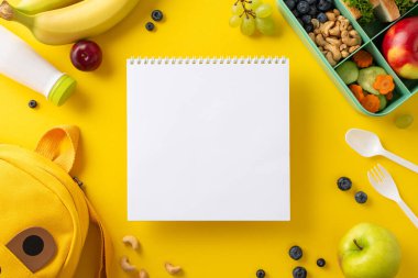 Plastik beslenme çantasının en üst görüntüsüyle, doğal gıdalar, yoğurt ve çatal bıçaklarla dolu okuldaki sağlığı destekleyin. Çizim için albüm, sarı arka planda komik sırt çantası, mesajınız için hazır.