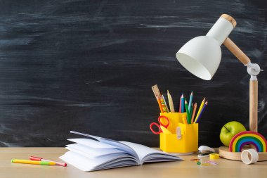 Çalışma alanınızı bu verimli öğrencinin işyeriyle optimize edin. Okul malzemelerinin yan görüntüsü ve ahşap masanın üzerindeki defter karatahta izole edilmiş arka plan, metin veya reklam için ideal.