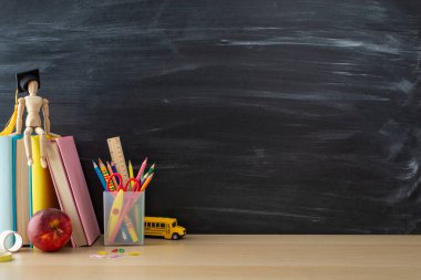 Okul temalı kurulum ile öğrenme aşkı geliştirin: masa başı gereksinimleri, kırtasiye standı, kitaplar, mankenler kara tahta zemin üzerinde yüksek lisans şapkası içinde, metin veya reklam için zorlayıcı bir alan yaratmak