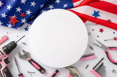 İşçi Bayramı 'nda kadınların katkısını kutluyoruz. Beyaz izole arka planda konfeti yıldızları ve inşaat araçlarıyla Amerikan bayrağının yer aldığı üstten çekim, reklam veya metin için yuvarlak çerçeve sunuyor