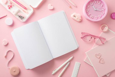 Pastel pembe arka planda öğrencilerin masa başlıkları. Okul malzemelerinin en üst görüntüsü: kalem kutusu, silgi, açık günlük, defterler, çalar saat, gözlük, mini zımba ve daha fazlası. Metin veya reklamlar için boşluk