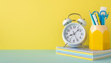 Okul konseptine geri dönelim. Çalar saat yığını fotokopi kitapları ve kalem tutacağı sarı duvar arka planında kalem cetvel makasıyla fotokopi alanı