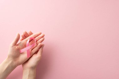 Uluslararası Göğüs Kanseri Farkındalığı Ayı konsepti. Yüksek açılı fotoğraf, kadınların ellerinde pembe kurdele tutarken pastel pembe izole arkaplanda metin ya da reklam için kopyalama alanı var.