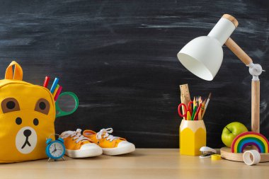 Çevrimiçi eğitim materyallerinizi, beyaz bir masanın, sırt çantanın ve okul malzemelerinin karatahta izole edilmiş arka planda, metin veya reklam anonim şirketi için tasarlanmış yan görüntüsü ile dönüştürün