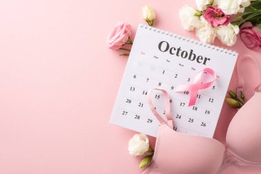 Pembe temalı sağlık tasarımı. Ekim takviminin üst görünüm düzenlemesi, pembe kurdele, sütyen ve pastel pembe arka planda östoma çiçekleri, metin veya reklam içeriği için yer sunar