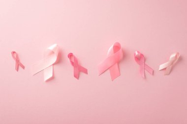 Göğüs kanseri destek konsepti. Pastel pembe arka planda pembe kurdele tabelalarının üst görüntüsü, reklam veya metin yerleştirme için mükemmel
