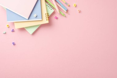 Moda okulunun aksesuar teması. Parlak renkli kalemler, kalemler, alfabe harfleri ve Pastel Pembe arkaplanda metin ya da reklam için yer olan kopya kitaplarının üst görünümü düz.