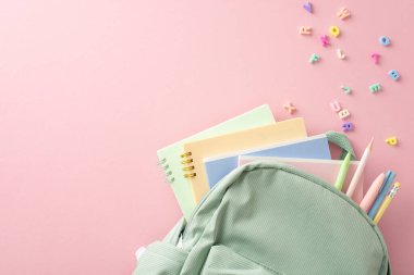 Liseli kızın araç gereçleri pembe arkaplandaki en üstten görüntülenmiştir: kalemli, kalemli, renkli defterli ve alfabe harfli bilge sırt çantası. Terfi için harika.