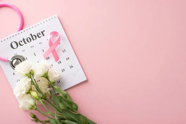 Health check reminder concept. Top view of October calendar, stethoscope, pink ribbon, and eustoma flowers on soft pink background, perfect for health campaigns or medical advertisements