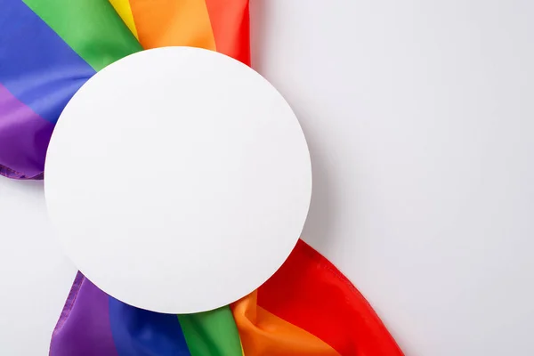 Standing together for equality: A rainbow flag, viewed from above on a white surface, makes a statement of support for LGBT history month, its blank space waiting to be filled with meaningful text