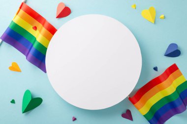 Temmuz ayında LGBTQ + Gurur Ayı 'nı canlı bayraklar ve gökkuşağı kalpleriyle kutluyoruz. Sakinleştirici açık mavi izole bir arkaplanda reklam veya metin için kopyalama alanı sağlayan üstten görünüm