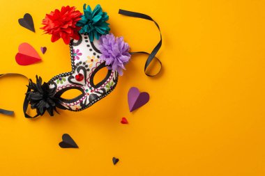 Day of the Dead-inspired carnival mask, lace and flowers form a skeleton design. Paper hearts too. Shot from top view on orange backdrop, room for text or ads clipart