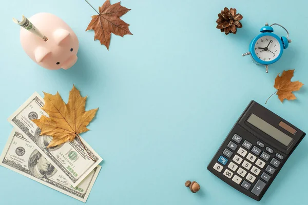 Escalation in prices and utility fees theme. Overhead shot of piggy bank, cash, calculator, alarm clock, maple leaves, acorns on muted blue backdrop with empty frame for text or promotion