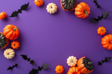 Cadılar Bayramı ruhuna yukarıdan aşağıya ürkütücü bir manzara ile dalın: menekşe arkaplan üzerinde küçük balkabakları ve yarasalar, selamlaşma ya da reklamlar için alan sunan