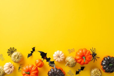 Ürkütücü cadılar bayramı konseptine dalmak. Sarı izole edilmiş arka planda balkabakları, örümcekler, yarasalar ve Cadılar Bayramı süslemelerinin yer aldığı yüksek açılı fotoğraf. Reklam veya metin için çok yönlü