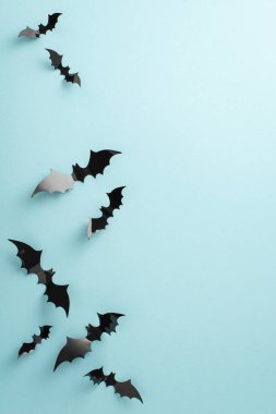 Ürkütücü Cadılar Bayramı gececi kavramının cazibesini tecrübe et. Mavi yalıtılmış yüzeyde dikey görüntü, kağıt yarasalar ve Cadılar Bayramı süslemeleri. Reklam veya metin için mükemmel