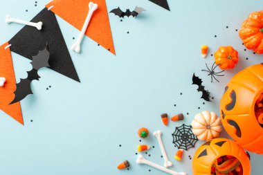 Çocukların Cadılar Bayramı şeker koleksiyonu. En üstteki resimde balkabağı sepeti gösteriliyor. İçi şeker dolu. Cadılar Bayramı süslemeleri mavi izole arka planda.