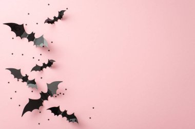 Şık Cadılar Bayramı şaka mı şeker mi fikri. Tematik elementlerin üst görüntüsü: Yarasa siluetleri ve yumuşak pembe arka planda yıldız şeklinde konfeti. Selamlama veya tanıtım için boş alan