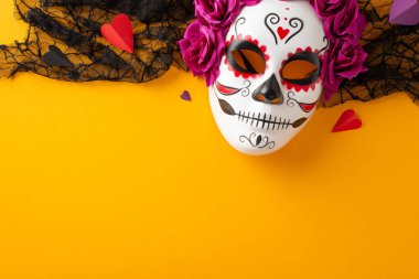 Büyük Dia de los Muertos festivalinin ruhuna katılın. Üst görünüm, sarı izole edilmiş arka planda canlı detaylarla süslenmiş bir kafatası maskesini gösteriyor. Metin için geniş alan