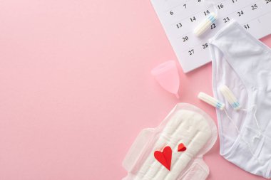 Feminine hygiene supplies like pad with red hearts, symbolizing blood, tampons, menstrual cup, underpants, calendar marking the cycle start, on a pastel pink background with room for text or branding clipart