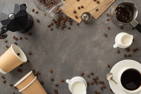 Coffee Lover's Delight: Top view of coffee beans, espresso cup, to-go cups, cream jar, coffee turk, measuring spoon, paper bags, and kettle on dark grunge background. Perfect for coffee enthusiasts ad