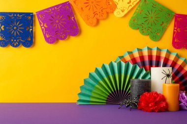 Ölü titreşimlerinin kaynaşma günü. Üzerinde canlı hayranlar, çiçek aranjmanları, mumlar, örümcekler ve sarı bir duvarın karşısında canlı bir çelenk bulunan mor bir masa üstü fotoğrafı.