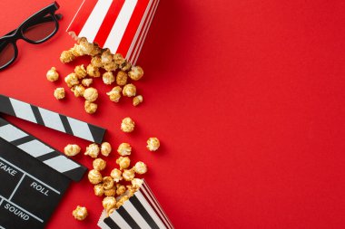 Patiler ile Blockbuster: üst görünüm peynir ve karamelli patlamış mısır, 3D gözlük ve kırmızı zemin üzerinde bir el çırpma tahtası, arkadaşlar arasında bir film gecesi için mükemmel bir atmosfer yaratıyor