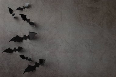 Cadılar Bayramı dileklerinizi bu üst görünüm ayarıyla düzenleyin: temalı dekor, desenli beton zemin üzerinde ürkütücü yarasalar, metin veya reklam için boş alan