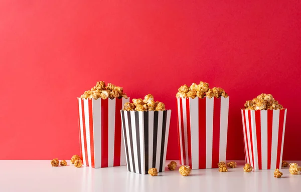 Join us for a cinema premiere with pals! A side-view photo showcases a table set with striped popcorn boxes against a red wall, ready for your text or adverts