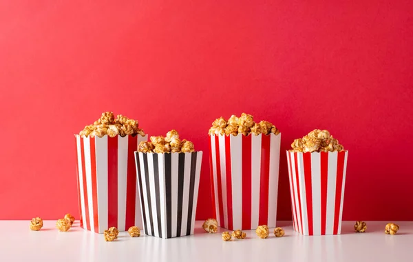 Film premiere with the crew! A side view photo of white table featuring striped popcorn boxes against a red wall background, with room for your text or advert